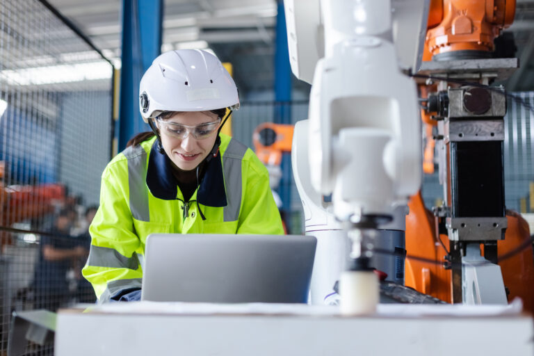 female technician engineer using laptop checking automation robo